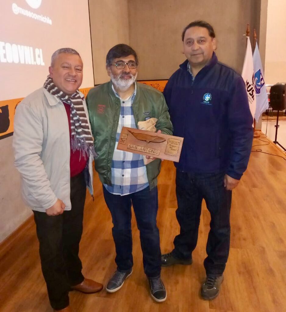 Manuel Meza, concejal de San Antonio y Juan Carlos Escalante, coordinador de MUSA, entregan reconocimiento al director del Museo OVNI, Cristian Riffo.